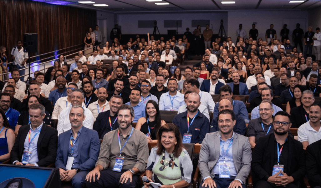 Auditório cheio de participantes do evento Top Magalog, todos sentados e olhando para a câmera.